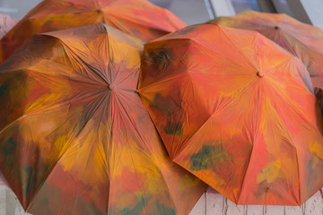 Fototapeta premium Several umbrellas painted in red-orange autumn colors. Fall background. Seasons.