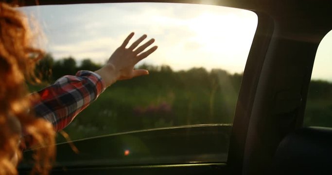 Close up shot of the girl stretching her hand towards the sun. On the road.