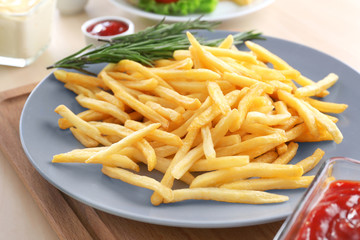 Plate with yummy french fries on table