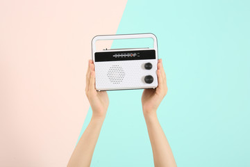 Woman holding radio on color background