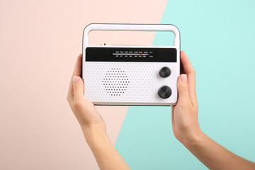 Woman holding radio on color background