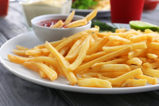 Plate with yummy french fries and sauce on table, closeup