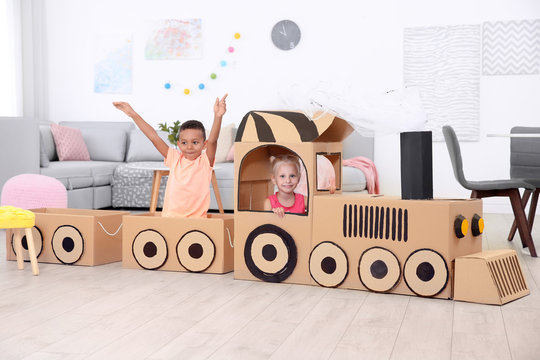Cute children playing with cardboard train at home