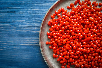 Plate with goji berries on wooden background