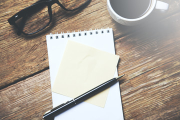 notepad with cup of coffee and glasses on table