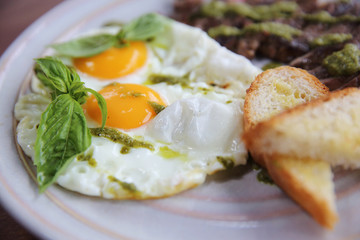 Fototapeta na wymiar Grilled beef steak with toast , fried egg and vegetables on top with pesto sauce