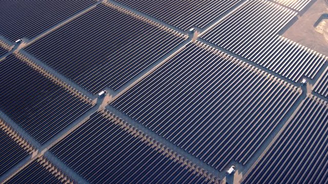 Aerial view flying over large solar farm in desert creating clean renewable energy 