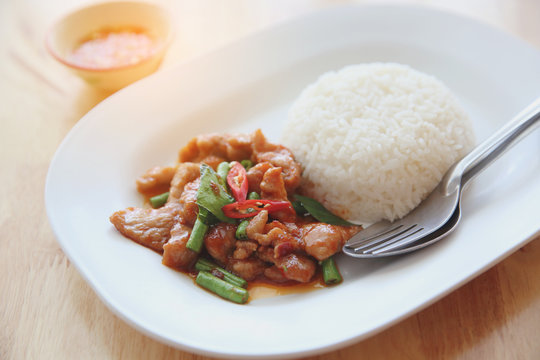 fried pork with thai curry and rice on wood background , Thai food