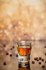 Cognac or liqueur, coffee beans and spices on a glass table.