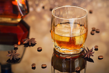 Cognac or liqueur, coffee beans and spices on a glass table.