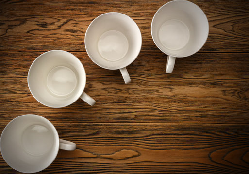 Four empty cups. White coffee Cup on wooden background. The view from the top. A place for a label.