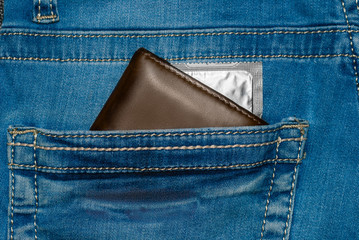 wallet in a pocket of blue jeans with silver condom