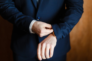 Handsome stylish man dressed in modern formal clothes jacket. Close up of hands of guy in blue jacket, white shirt. Person ready for wedding celebration, graduation or business meeting. Closeup