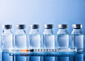 Row of vials and syringe on blue table front view