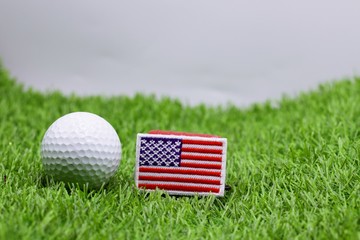 Golf ball and USA flag on green grass