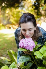 Fototapeta premium Beautiful woman crouching while smelling at purple hydrangea
