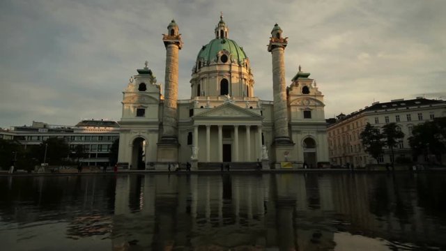 Sunset at Karlsplatz square with Karlskirche church reflecting in the fountain
