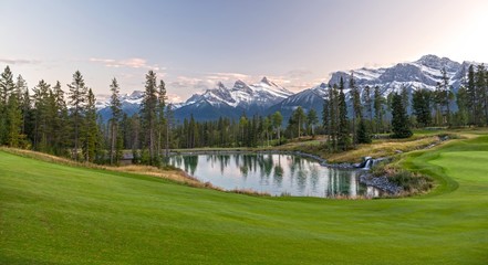 Silvertip Golf Course Green and Distant Landscape View of Three Sisters Snowy Mountain Tops above Town of Canmore in Foothills of Rocky Mountains Alberta Canada - obrazy, fototapety, plakaty