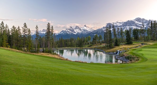 Silvertip Golf Course Green and Distant Landscape View of Three Sisters Snowy Mountain Tops above Town of Canmore in Foothills of Rocky Mountains Alberta Canada