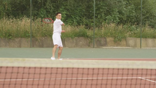  Male tennis player playing against unseen opponent on outdoor court