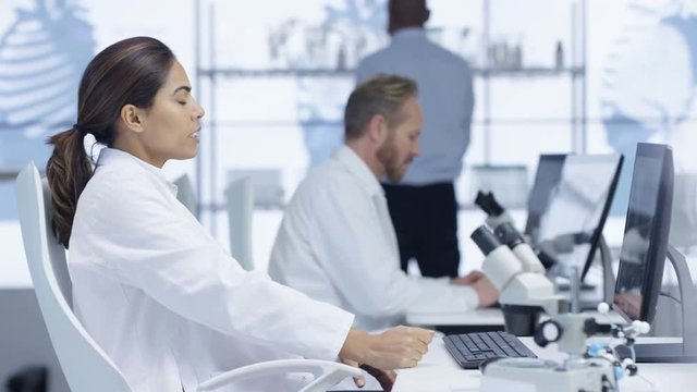  Medical researchers in the lab, working on computers & discussing their work