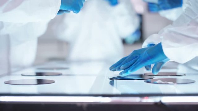 Scientific Research Team Wearing Full Body Suits Examining Hi-tech Materials In Sterile Lab.