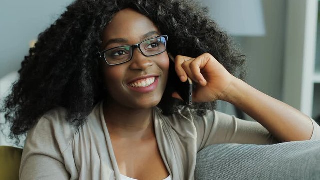 Beautiful curly African American woman speaking on the phone and nodding her head. Indoor. Portrait shot. Close up