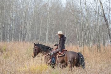 young woman riding horseback in tall grass