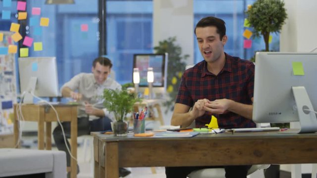  Young designers fooling around & throwing rolled up papers in creative office