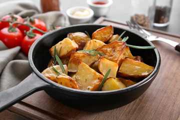 Delicious baked potatoes with rosemary in pan on table