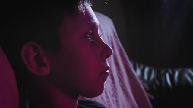 Little boy watching a movie on on TV and eating popcorn