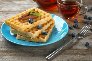 Plate with delicious cinnamon waffles on table