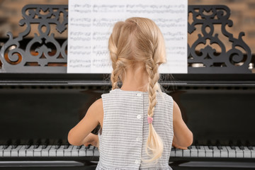 Little girl playing piano indoors
