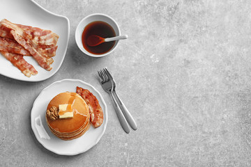 Plate with pancakes and bacon on table
