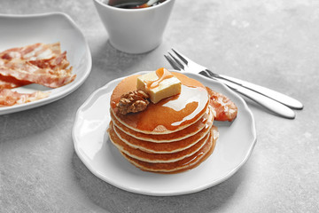 Plate with pancakes and bacon on table