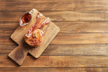 Wooden board with pancakes and bacon on table