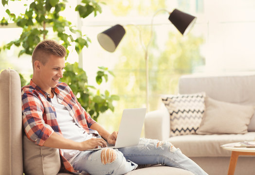 Young man with laptop on sofa at home