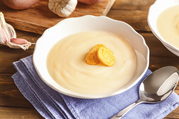 Potato cream soup in bowl on table