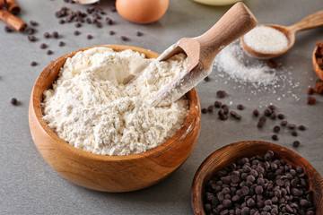 Bowl and scoop with flour on gray table