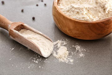 Scoop and bowl with flour on gray table