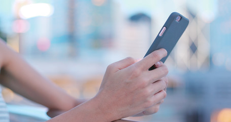 Woman using her mobile phone, city skyline night light background