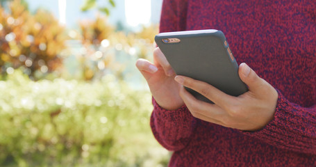 Woman using cellphone with autumn scene