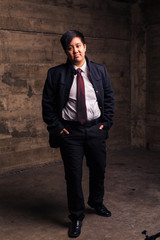 Young transgender man in formal clothing poses in a grungy urban location