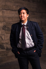 Young transgender man in formal clothing poses in a grungy urban location