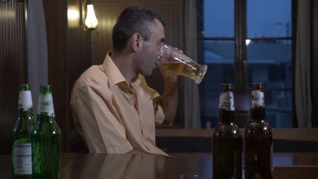 Addicted to alcohol depressed guy drinks beer at the bar in a weekend evening