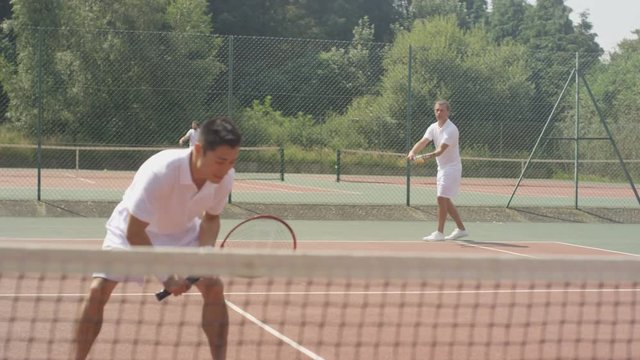  Male doubles tennis players serving & scoring a point on outdoor court