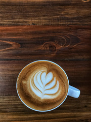 Heart Latte art coffee in white cup on the wooden table. Wake up and full fill energy, top view.