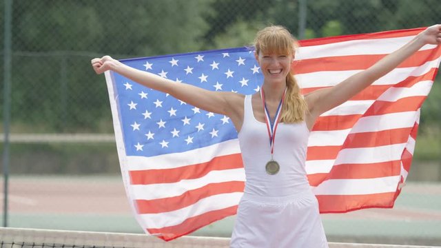 Portrait smiling female tennis player with USA flag and gold medal