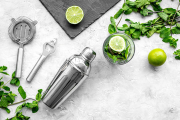 In the bar. Shake mojito. Lime, mint., barman tools on grey background top view copyspace