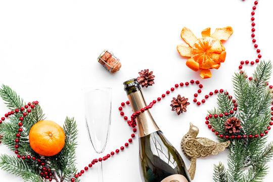 New year eve background. Spruce branch, glasses, champagne bottle, tangerines on white background top view copyspace